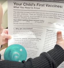 baby with vaccine info sheet