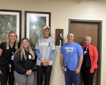 GH staff with Scott by the cancer bell donated by his family