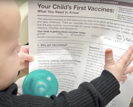 baby with vaccine info sheet