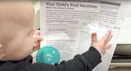 baby with vaccine info sheet