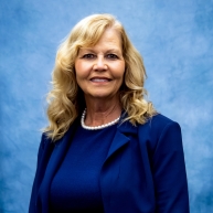 Headshot of Jackie in blue dress with blazer