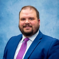 Brennon Malcom in a blue blazer with a light blue shirt and pink tie