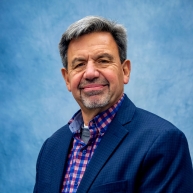 Karl Randecker in a blue blazer with pink and blue checked button-down shirt
